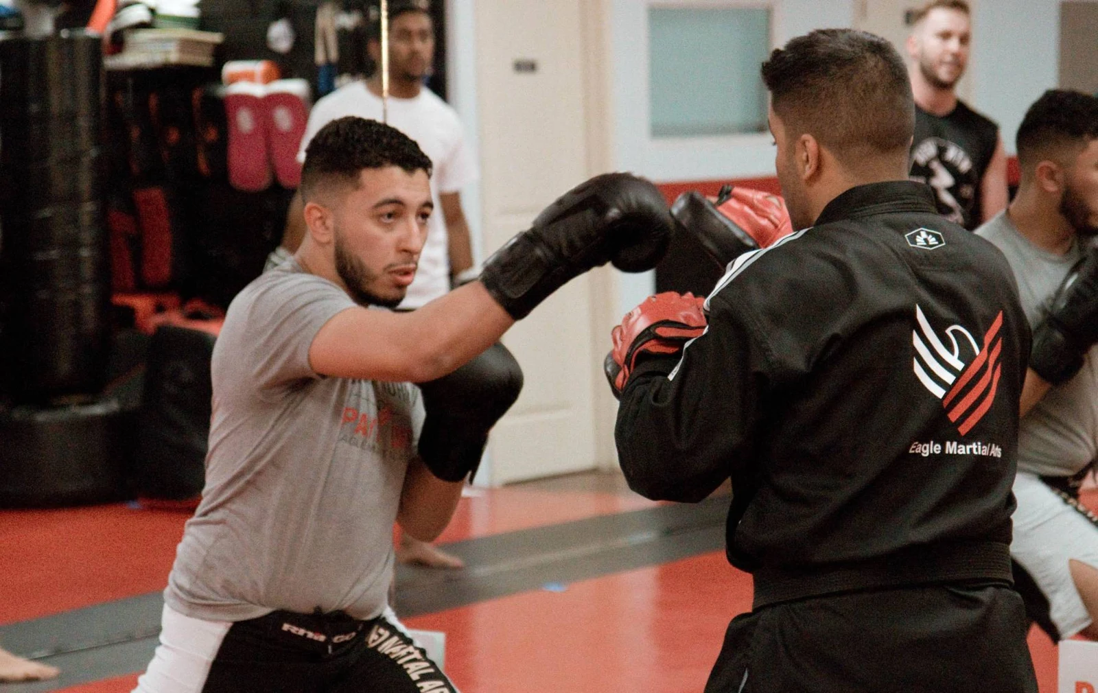 Adults working striking pads with a coach